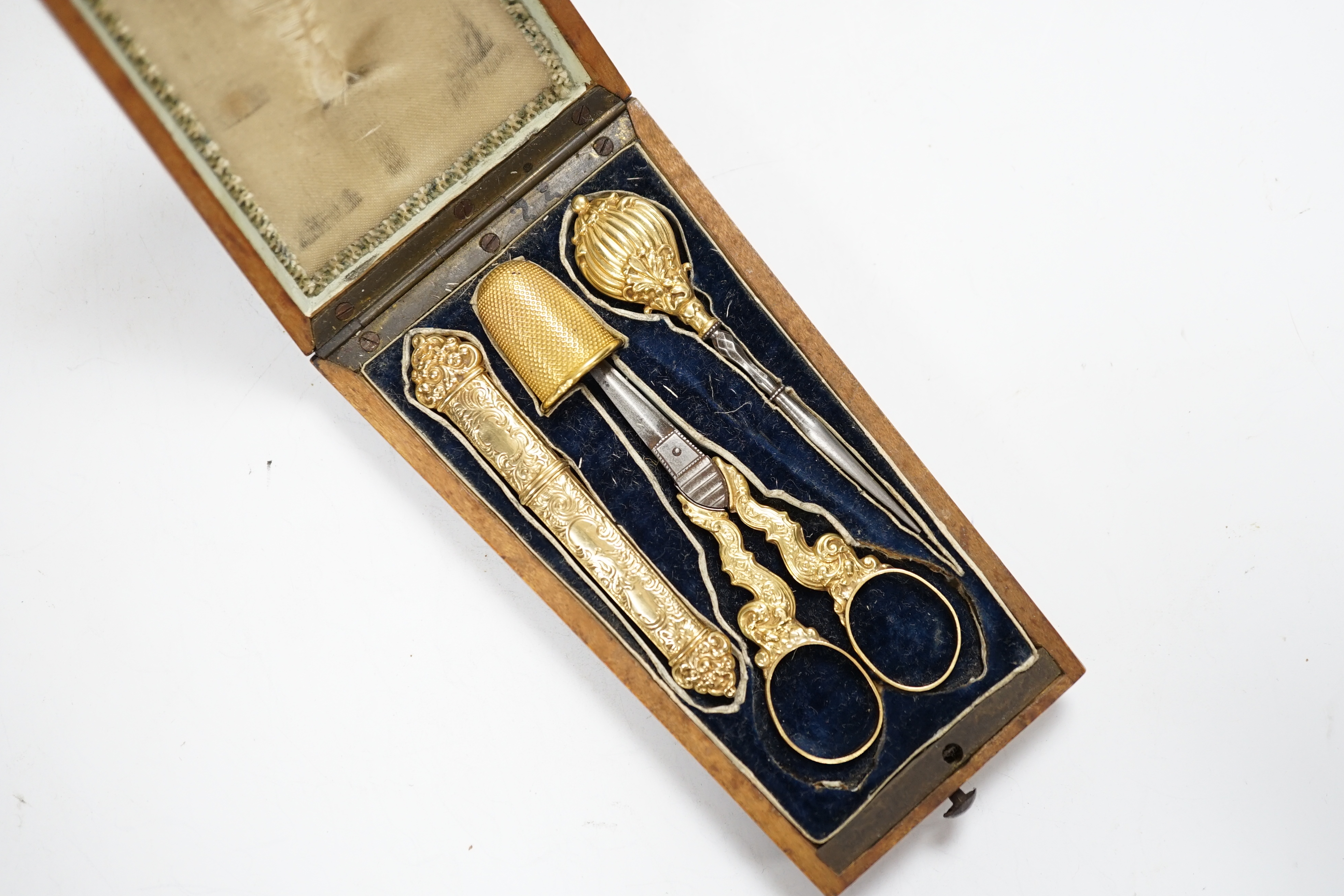 A French four piece yellow metal (18ct poincon mark) necessaire, comprising a thimble, pair of mounted scissors, hole maker and needle case, in fitted rosewood case.